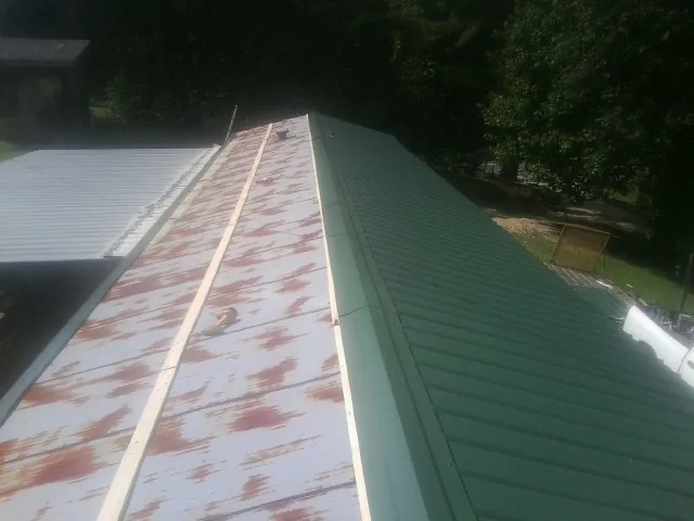 Old rusted panels beside newly installed green metal roofing — Wind Damage Roof Repair by Roofing Brothers in Swansea