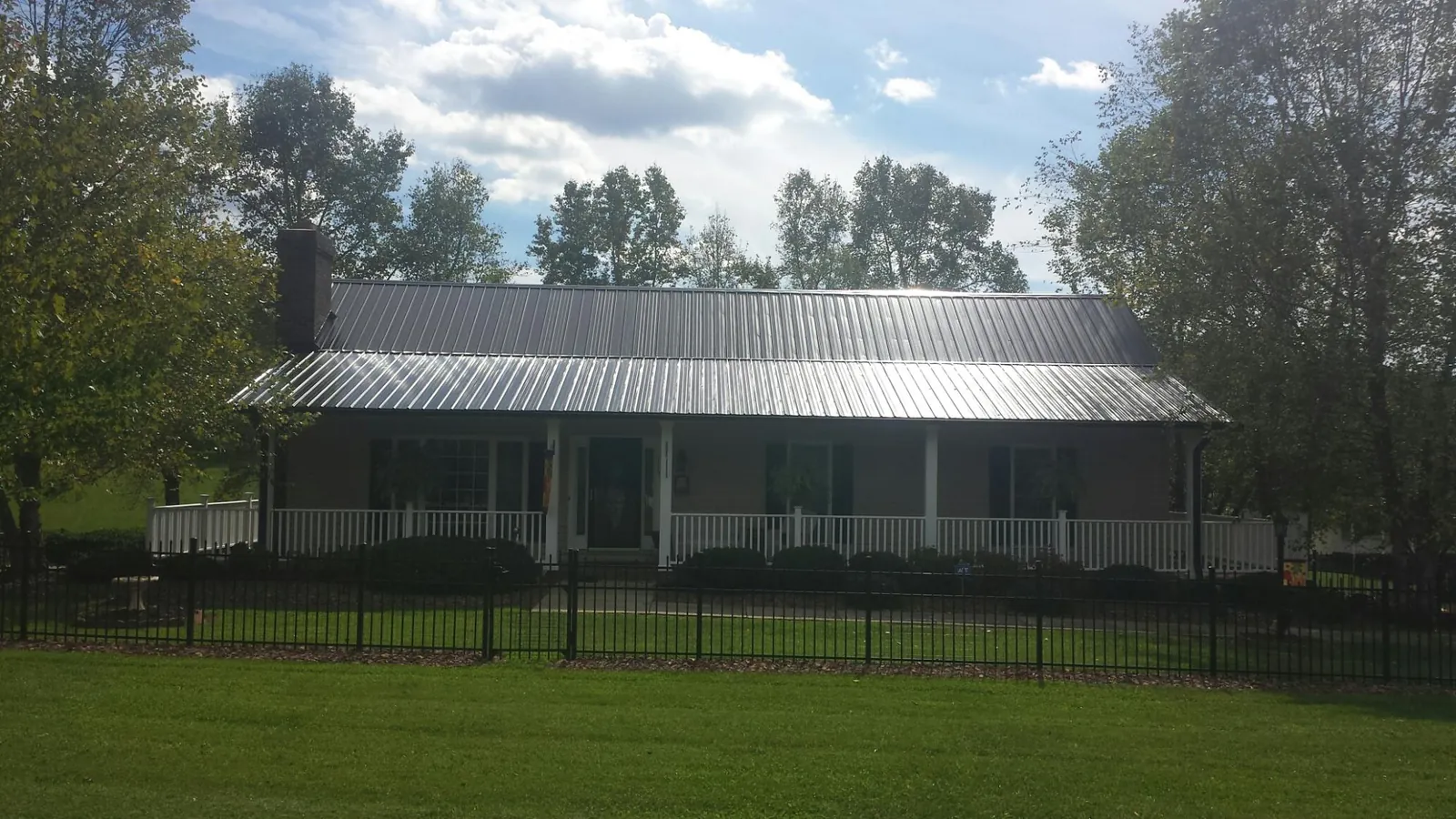 Gray metal roof on a brick ranch with a full width front porch — Gutter Guard Installation work by our crew in Swansea